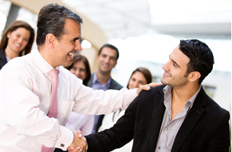 Employer warmly greeting employee with handshake and pat on shoulder
