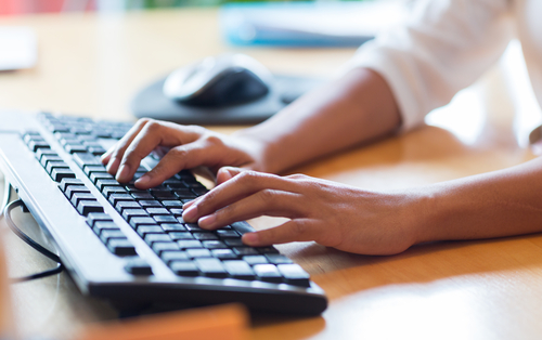 Hands typing on keyboard that is too small for office employee with obesity