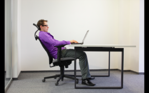 Office worker slouching in chair at desk with laptop, not in comfort
