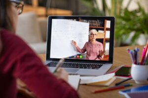 Student on laptop watching teacher teaching from home