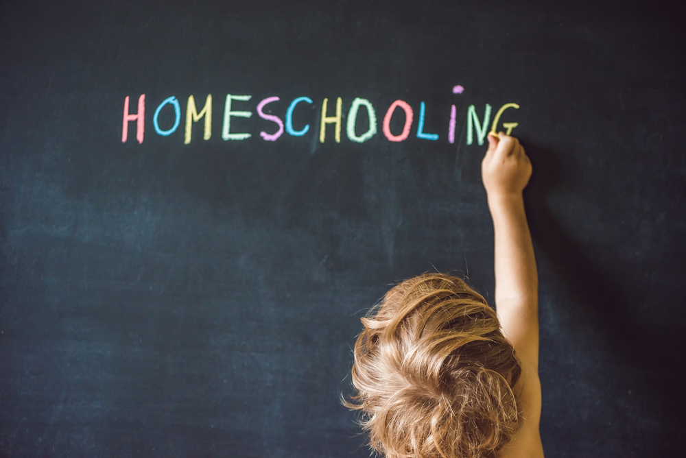 child writes homeschooling on blackboard