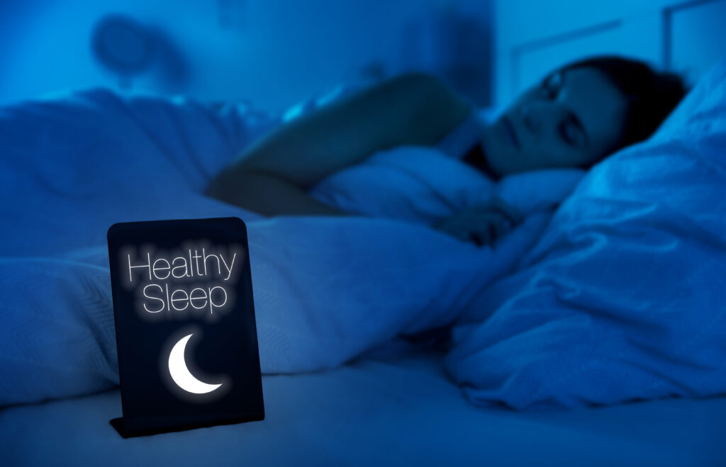 Woman with good sleep hygiene in bed in dark room sleeping deeply with healthy sleep sign